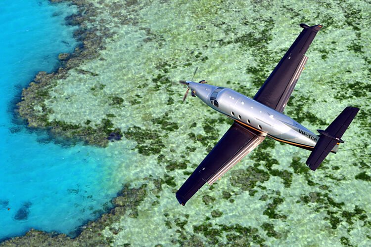 Avião da Amaro Aviation sobrevoando localidade de praia.